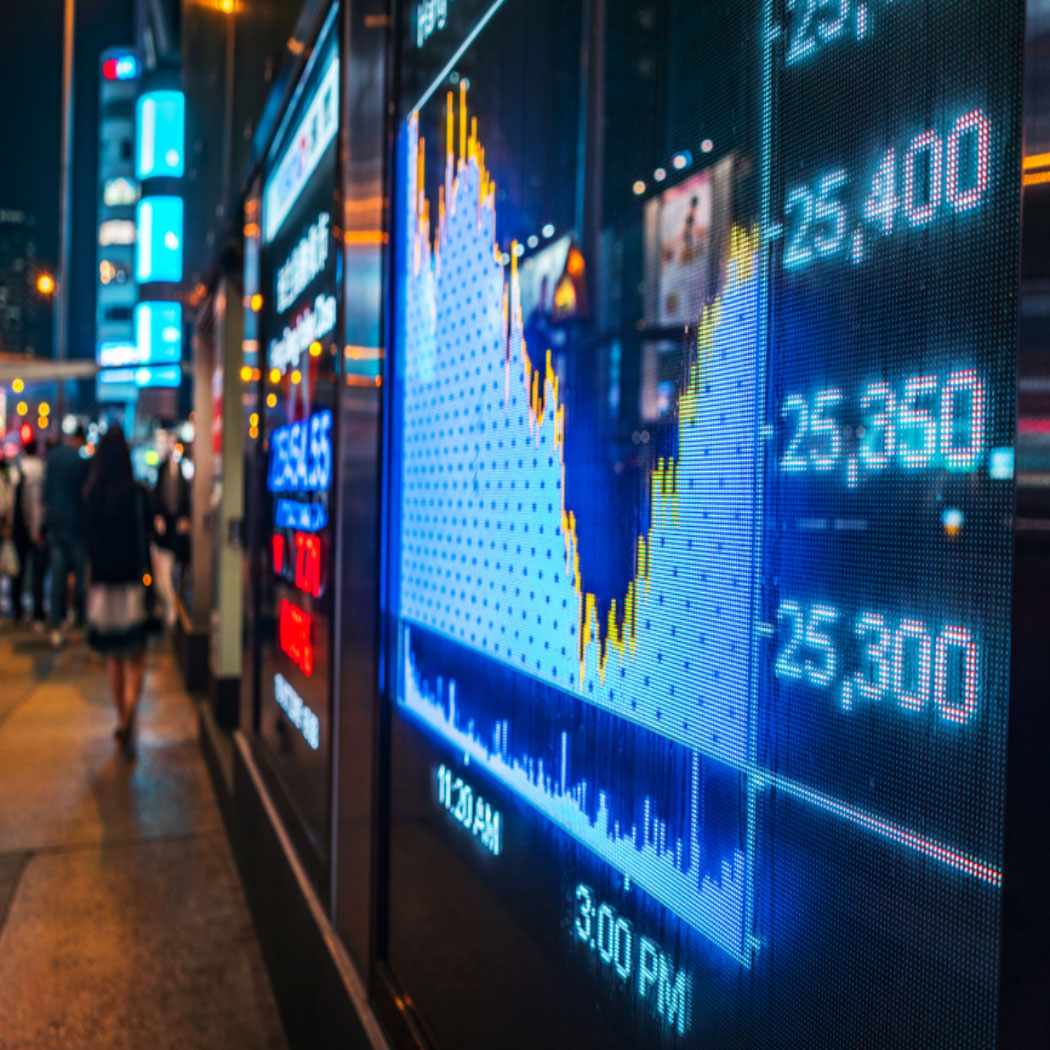Television screen on city sidewalk at night showing stock market charts, Banking & Capital Markets | DXC Technology